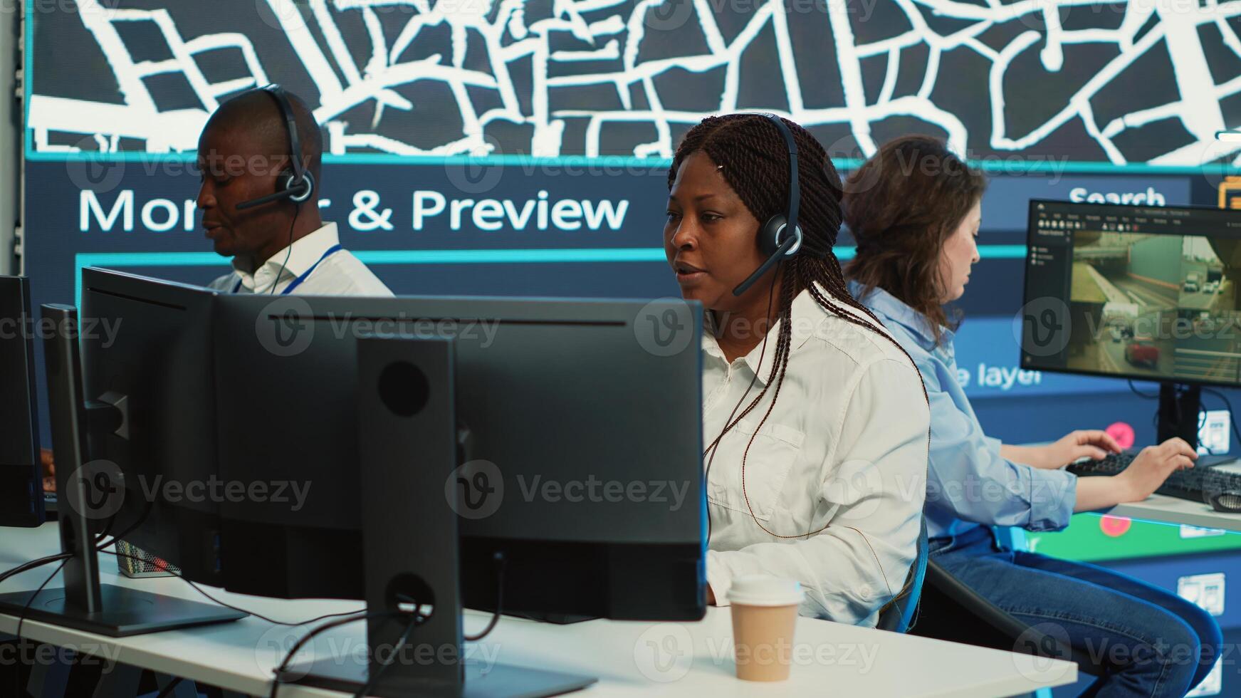 Diverse team of operators providing order tracking updates to clients, following delivery trucks around the city via gps coordinates and satellite map. Using surveillance CCTV footage. Camera A. photo