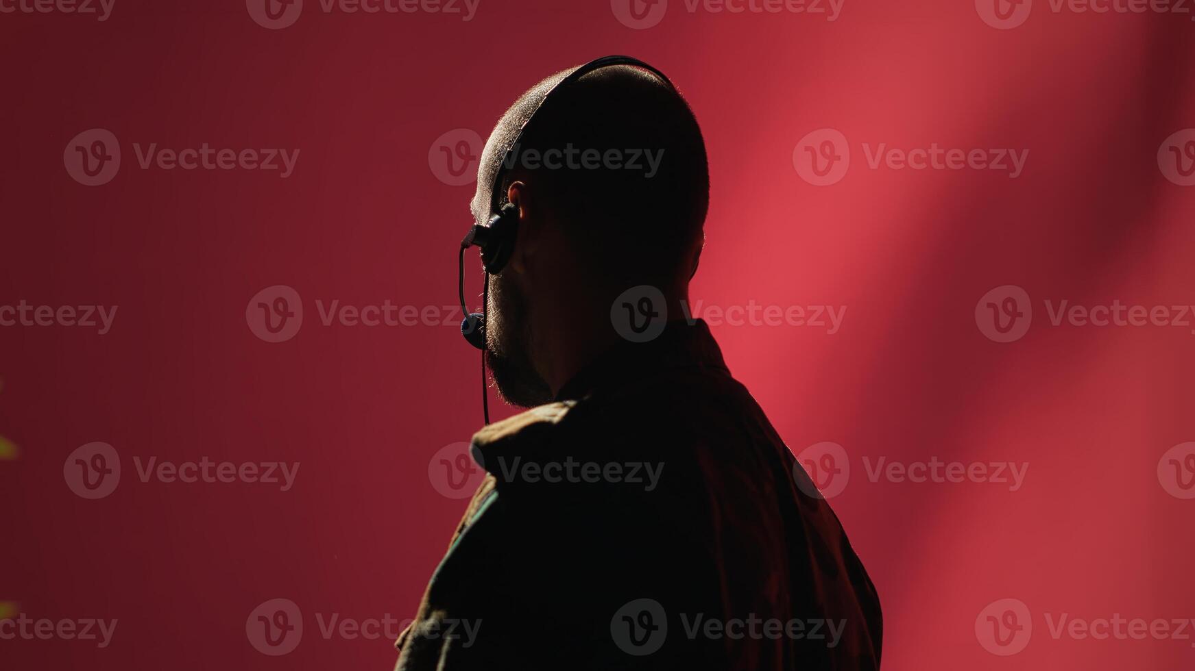 Military dispatcher providing informations for troops on war front lines, talking in headset microphone. Radio communications operator in uniform coordinating troops, camera A photo