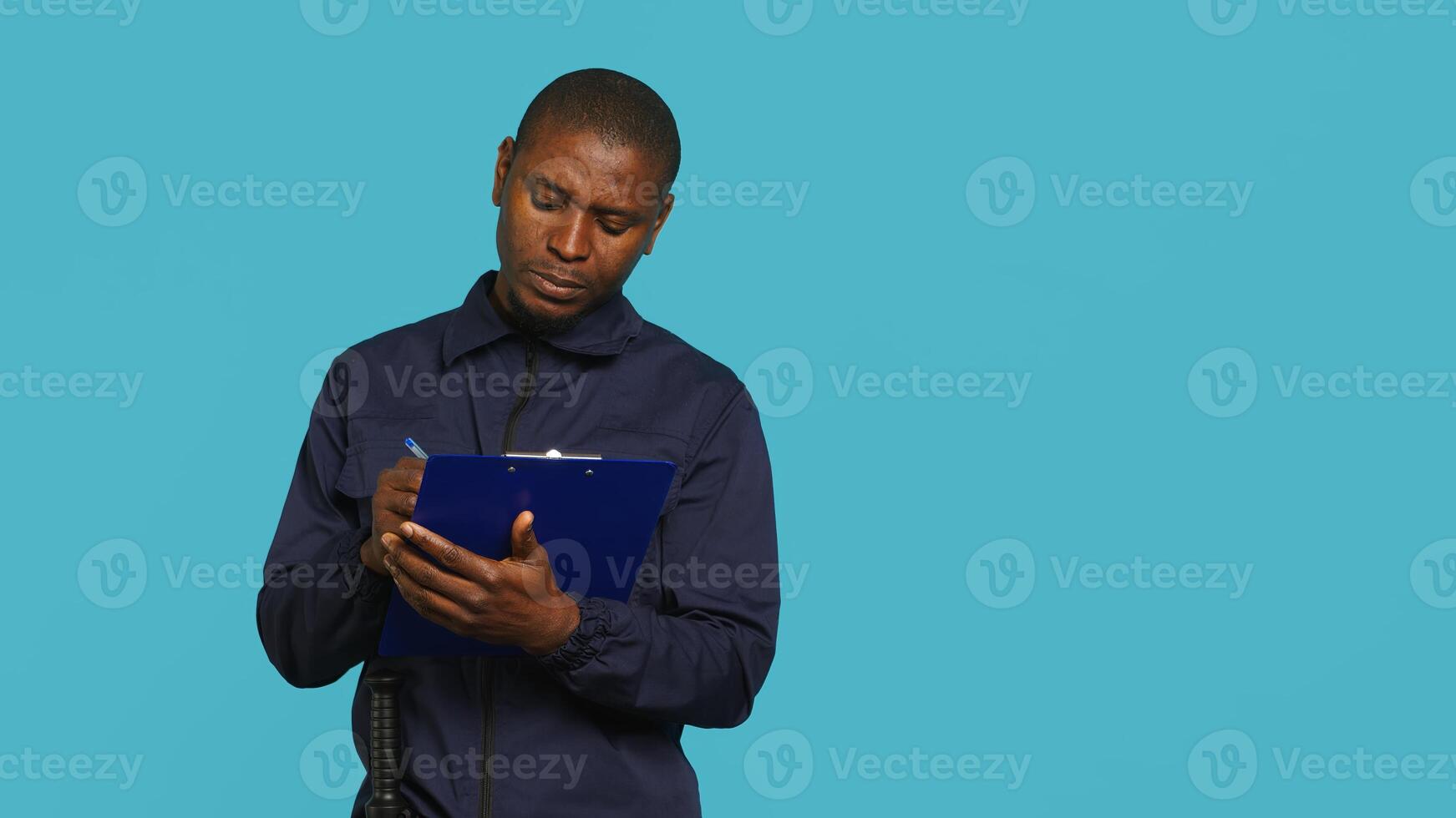 Security guard holding clipboard, taking notes, receiving orders during protection job shift. Portrait of bodyguard using pen to write informations received, studio background, camera A photo
