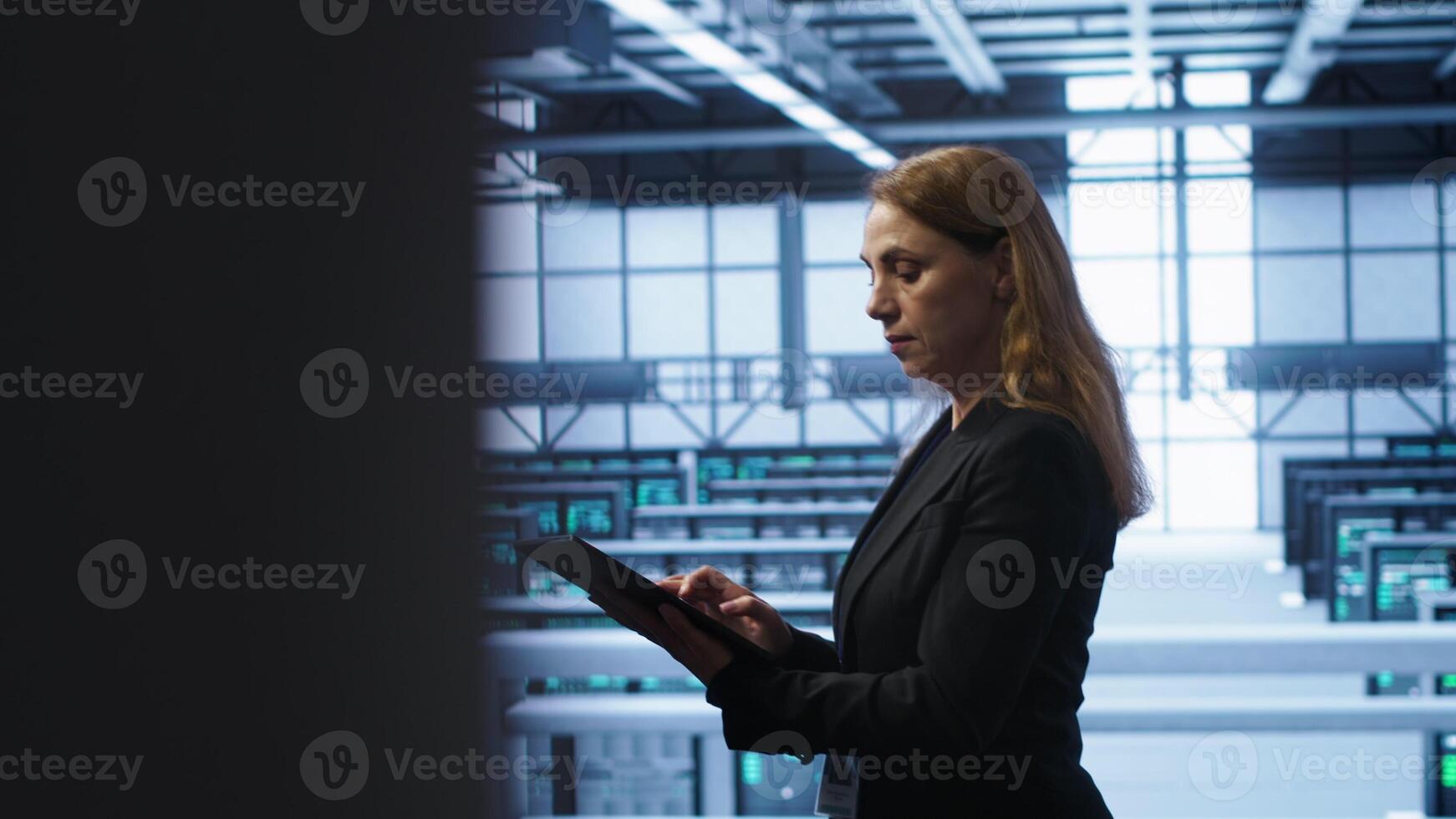 Computer scientist doing checkup, inputting data on tablet of needed fixes in server hub. Woman working in data center housing advanced data storage infrastructure supporting IT workloads, camera A photo