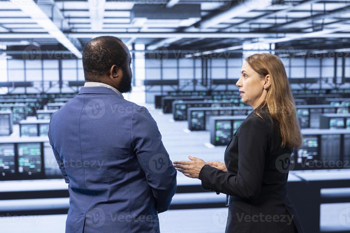 Management executive overseeing data center, checking security enforcement, ensuring business continuity. People in server farm maintaining compliance with industry regulations photo