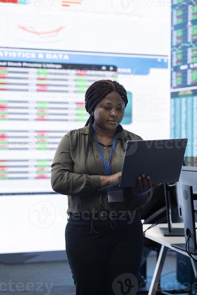 Chief financial officer studying capital funds and revenue data on big screen and laptop, verifying annual reports and budget allocation for a project. Looking for ways to increase profit. photo