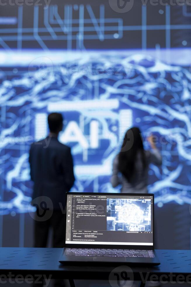 Focus on complex AI brain models being analyzed on laptop by developers in blurry background. Close up of machine learning on notebook used by teamworking IT staff members to develop AI photo