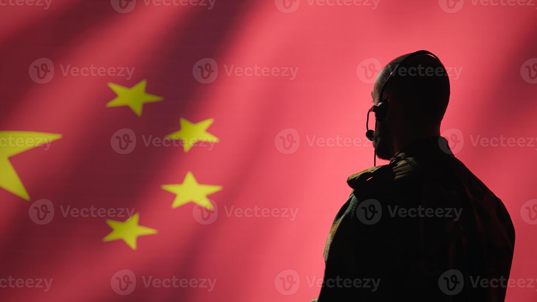 Military dispatcher working for Chinese army relaying info for troops using headset. Radio communications operator isolated over China flag background coordinating soldiers through headphones photo