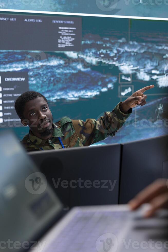 Army specialists use advanced computer systems and big screen to gather intelligence, studying radar satellite data to enhance national security. High tech military control room base of operations. photo