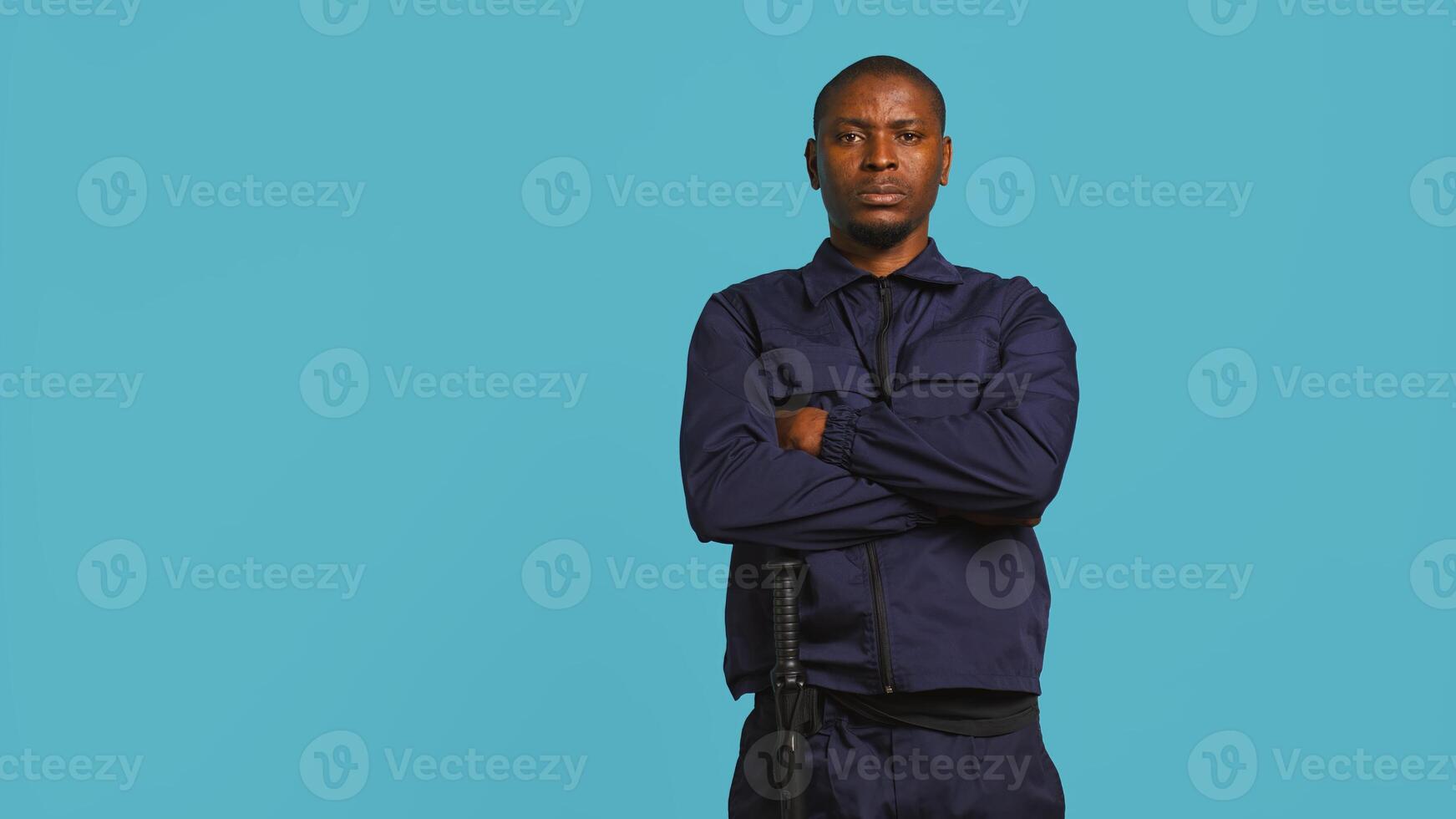 Security guard does surveillance for various organizations and venues, ensuring protection of property and personnel, studio background. Portrait of intimidating man in uniform crossing arms, camera B photo