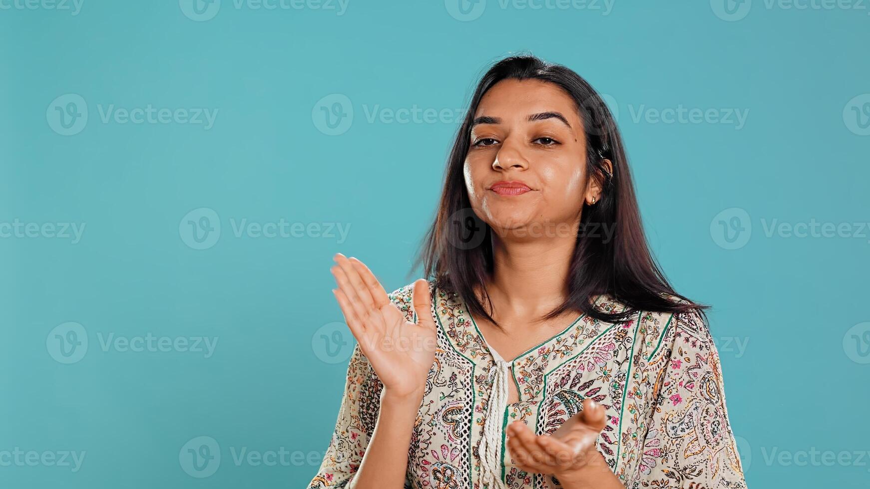 Portrait of envious indian woman mockingly clapping hands, showing frustration, studio backdrop. Resentful sassy person rolling eyes and applauding in jest, feeling irritated, camera B photo