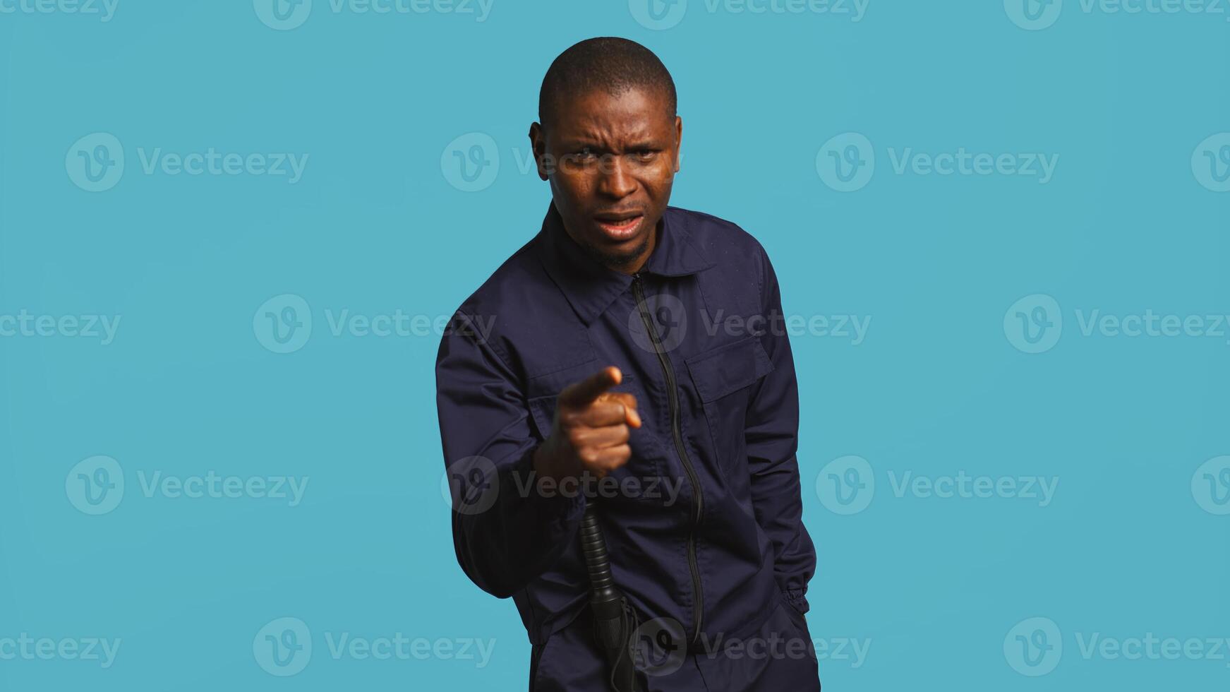 Security guard pointing finger, scolding people for trespassing on private property. Portrait of stern bodyguard berating unwanted visitors for entering restricted area, studio background, camera B photo