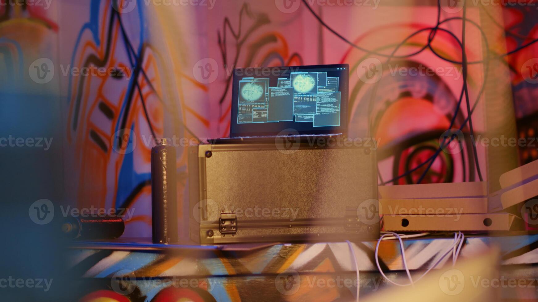 Laptop in underground bunker with graffiti painted walls left behind by hackers to act as decoy, running script pinging wrong location to cybercriminal law enforcement chasing them photo