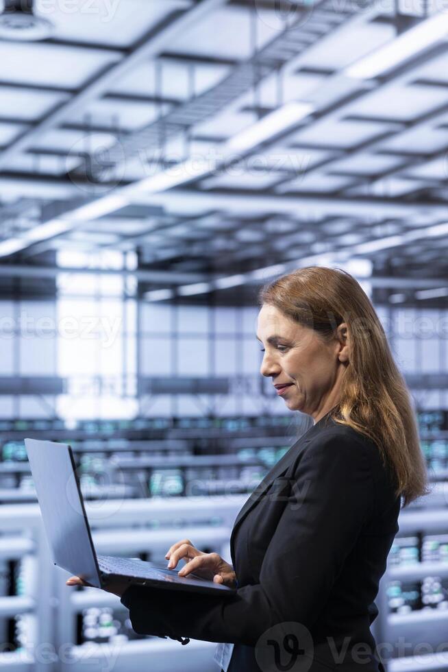 Data center system administrator ensuring safety and security of database using laptop. IT staff member in server farm preventing unauthorized access posing risks for company photo