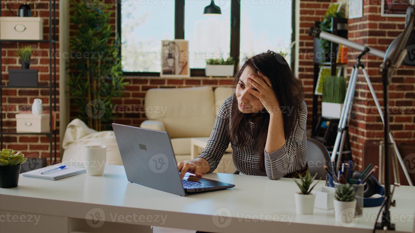 Self employed woman feeling ill, struggling to concentrate while working from home, hurting from headache. Exhausted freelancer suffering from sickness and stress while working on laptop, camera A photo