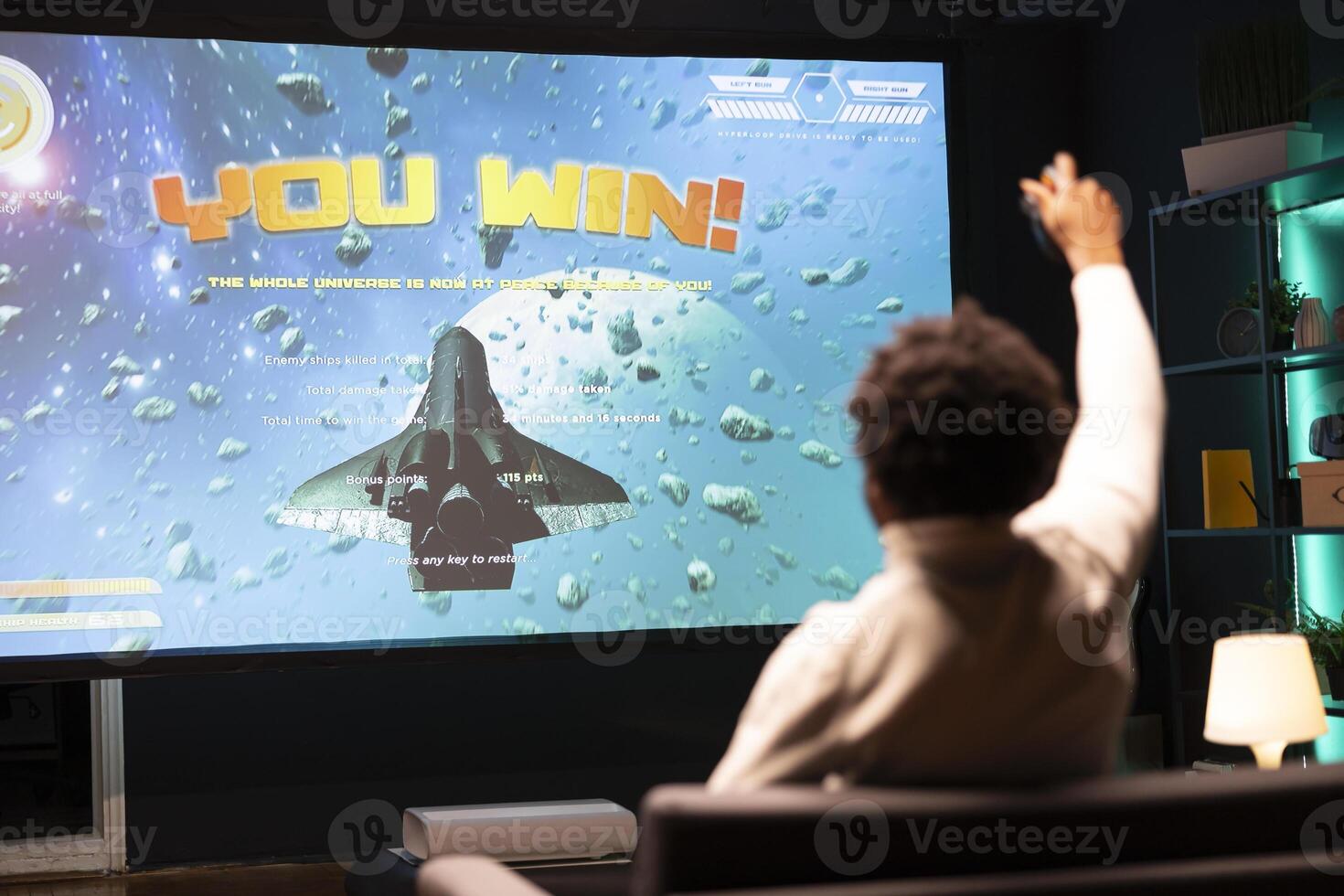 Man playing videogames on gaming console, celebrating victory. Gamer excited after winning online multiplayer game match on widescreen smart TV, rejoicing, throwing fist in air photo