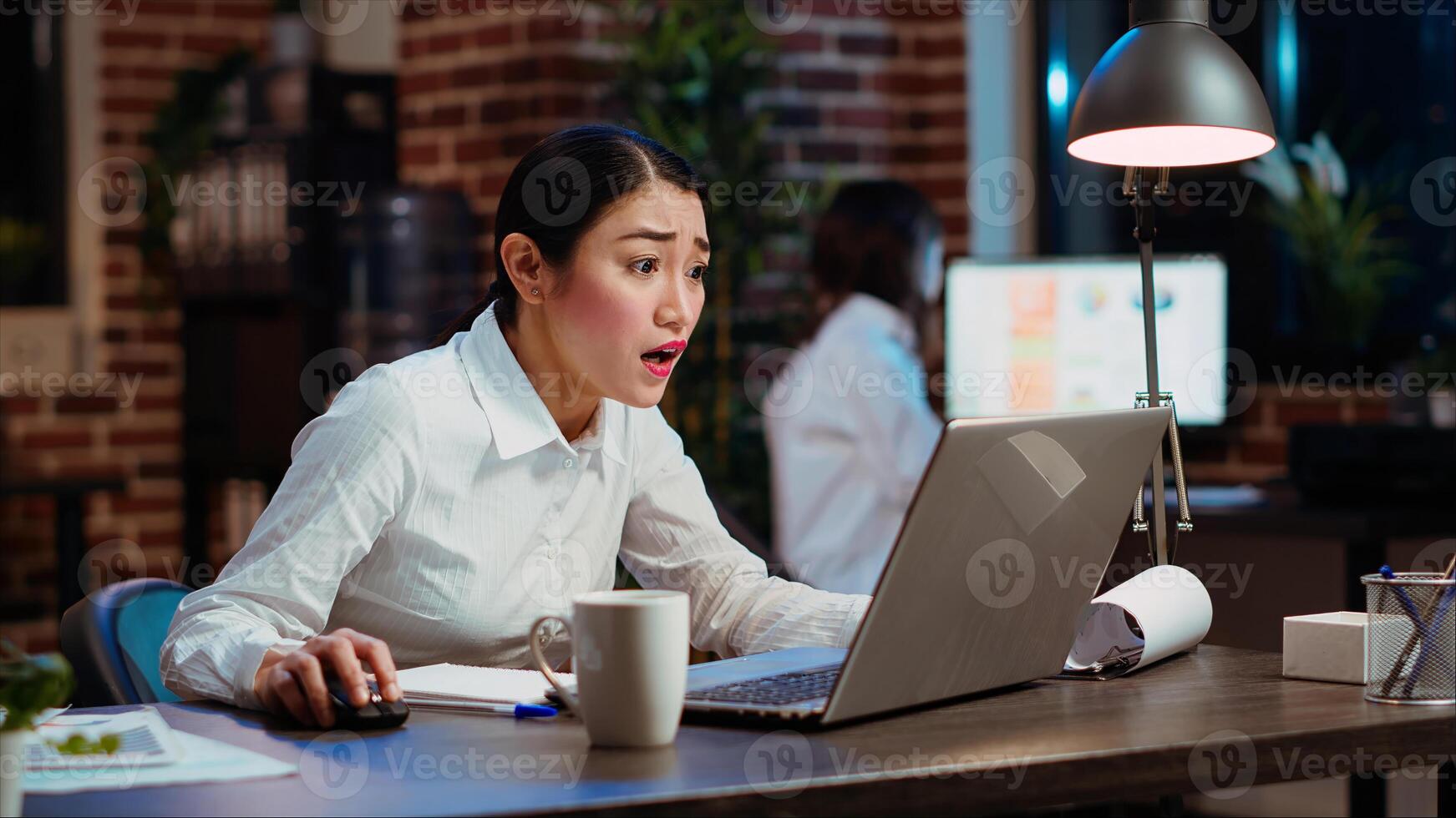Asian employee gasping, shocked by negative response received from customer while discussing business matters over email. Worker wincing while looking at laptop screen, feeling disappointed photo