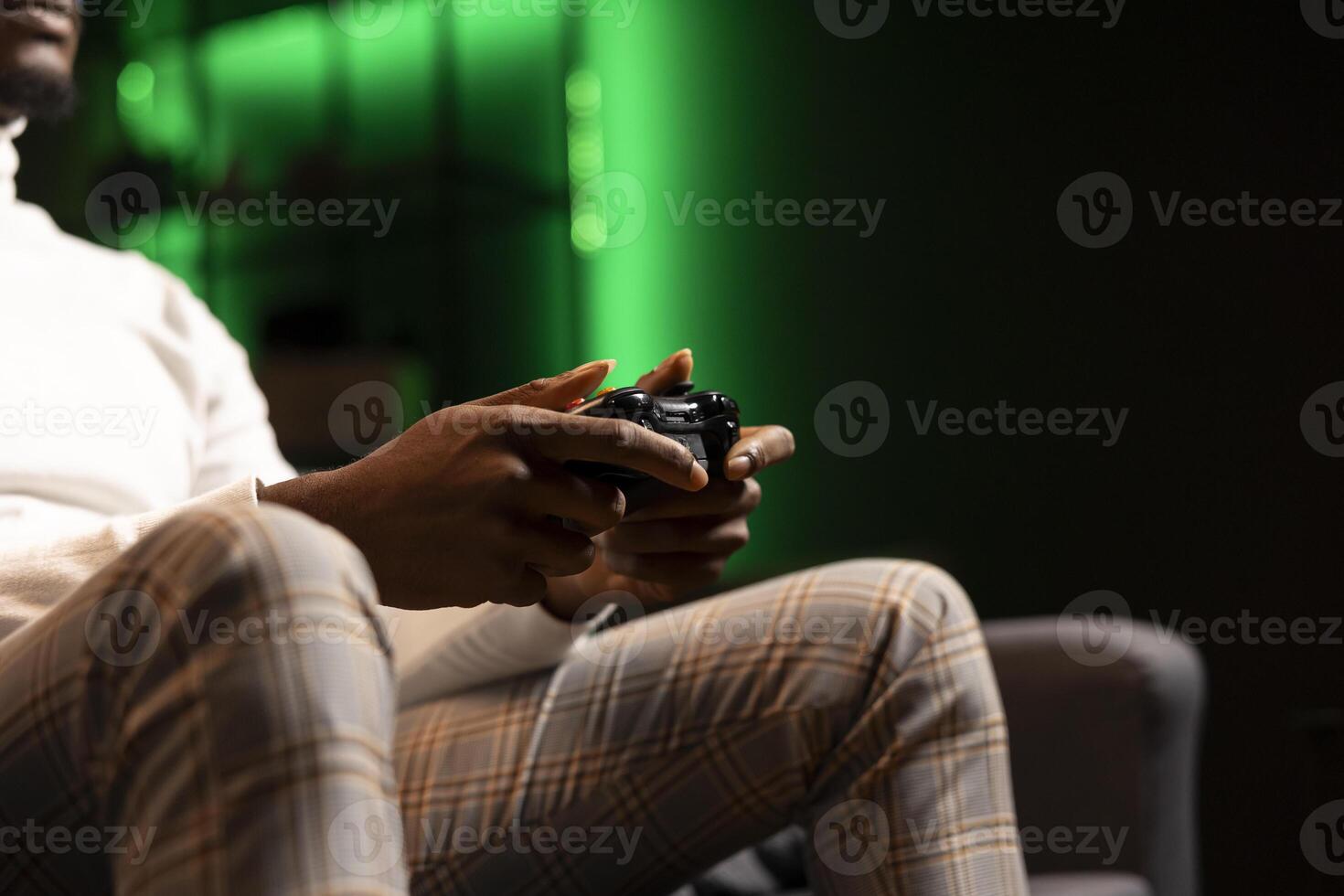 Man holding controller in green neon illuminated apartment, playing videogames. Gamer on couch using joystick to participate in PvP online multiplayer game on console system, relaxing and having fun photo