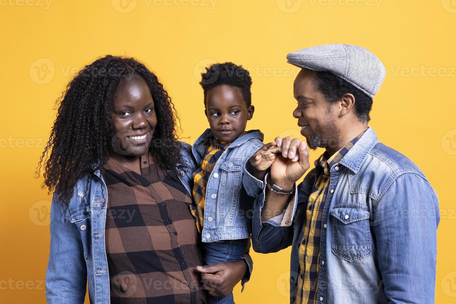 African american happy family posing together on camera, smiling couple embracing their small baby boy. Cheerful young mom and dad showing affection to their toddler in studio. photo