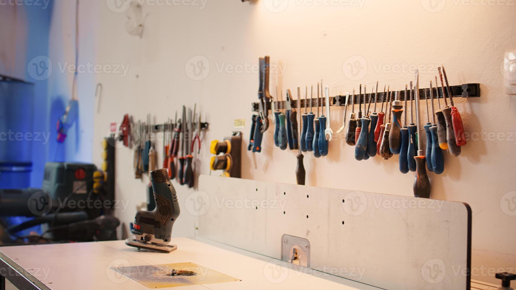 Close up of electric router on spindle moulder in furniture assembly shop with woodworking tools on rack in background. Focus on hand powered equipment used for sanding wood in studio, panning shot photo