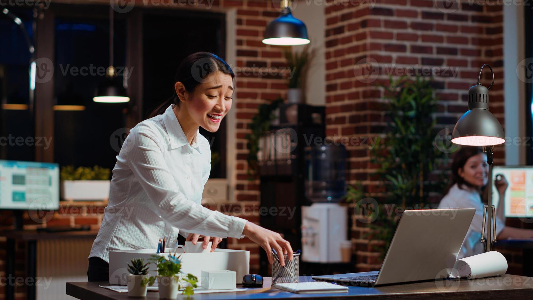 Woman dancing and singing while packing desk belongings, excited to change offices after job promotion. Joyful employee being advanced in company hierarchy, celebrating, saluting colleague, camera B photo