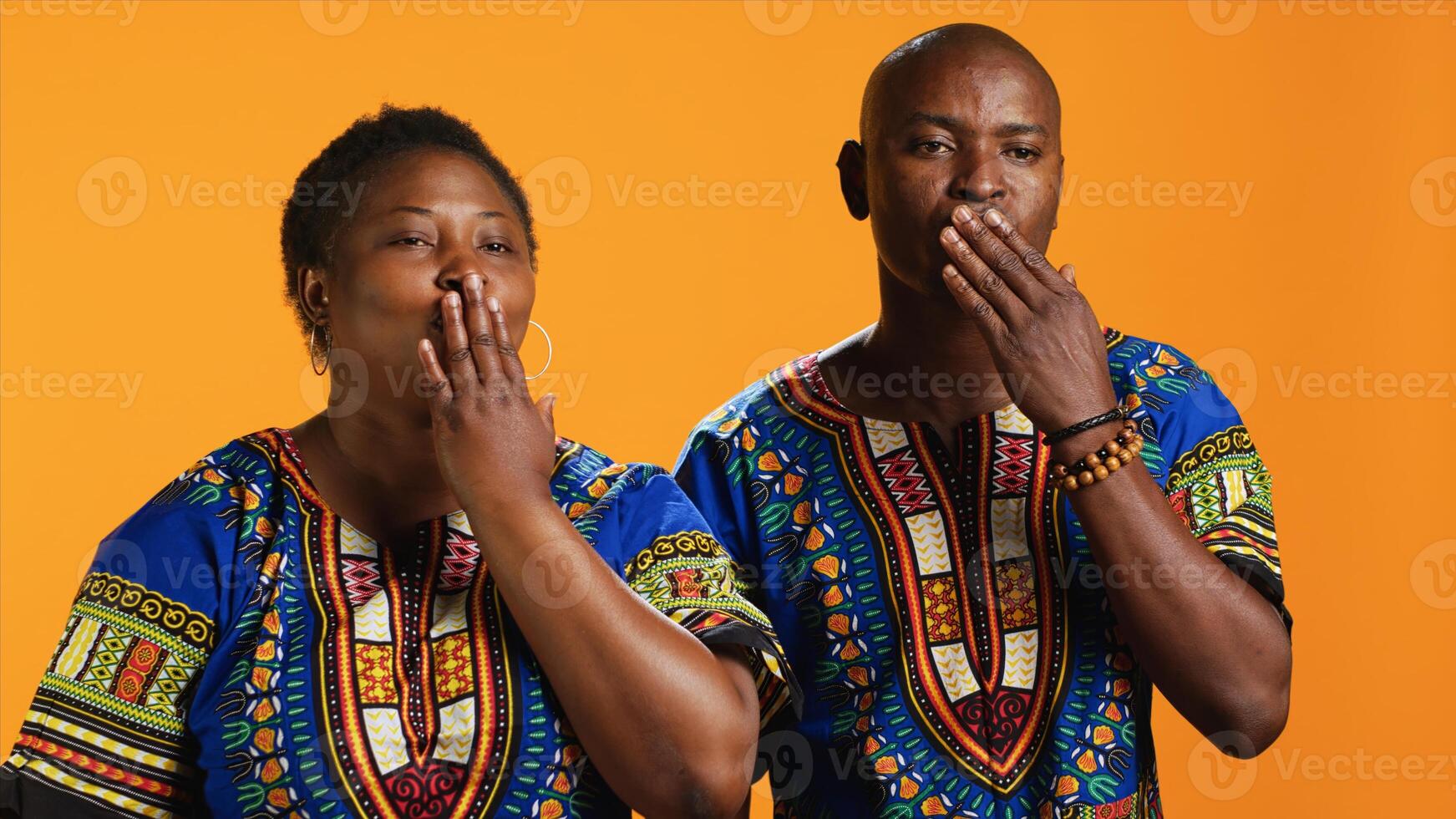 Ethnic couple blowing air kisses in front of camera, doing romantic flirty gesture in studio and sharing love. African american married people sending kiss to someone, affection symbol. photo