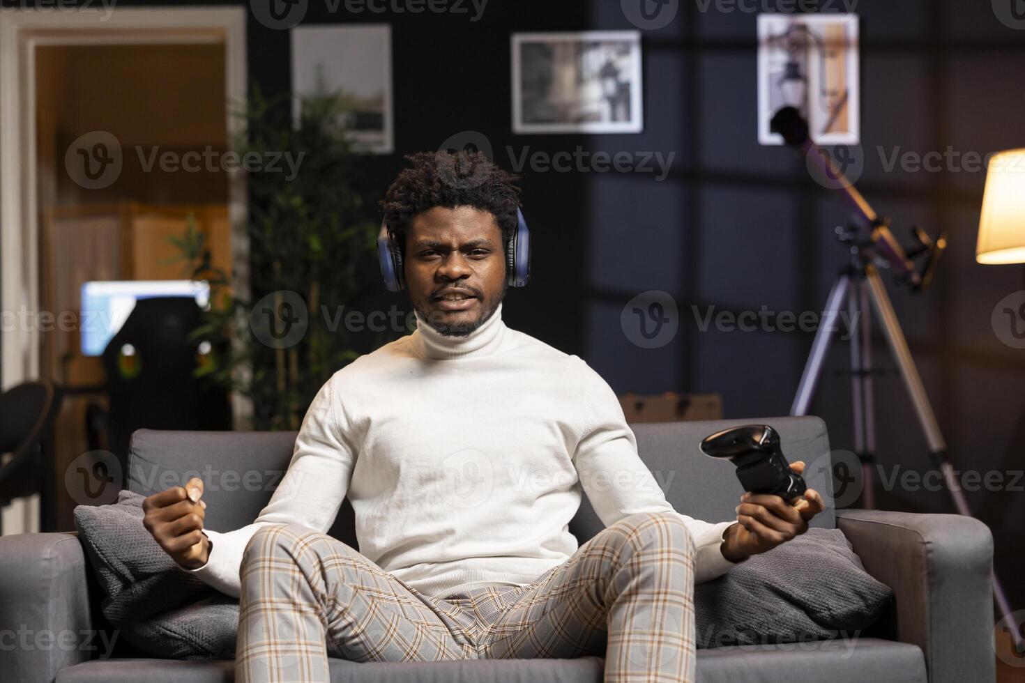 Cheerful BIPOC man playing videogames on gaming console, celebrating victory after conquering all rival players. Gamer excited after winning game, displaying happiness emotions photo