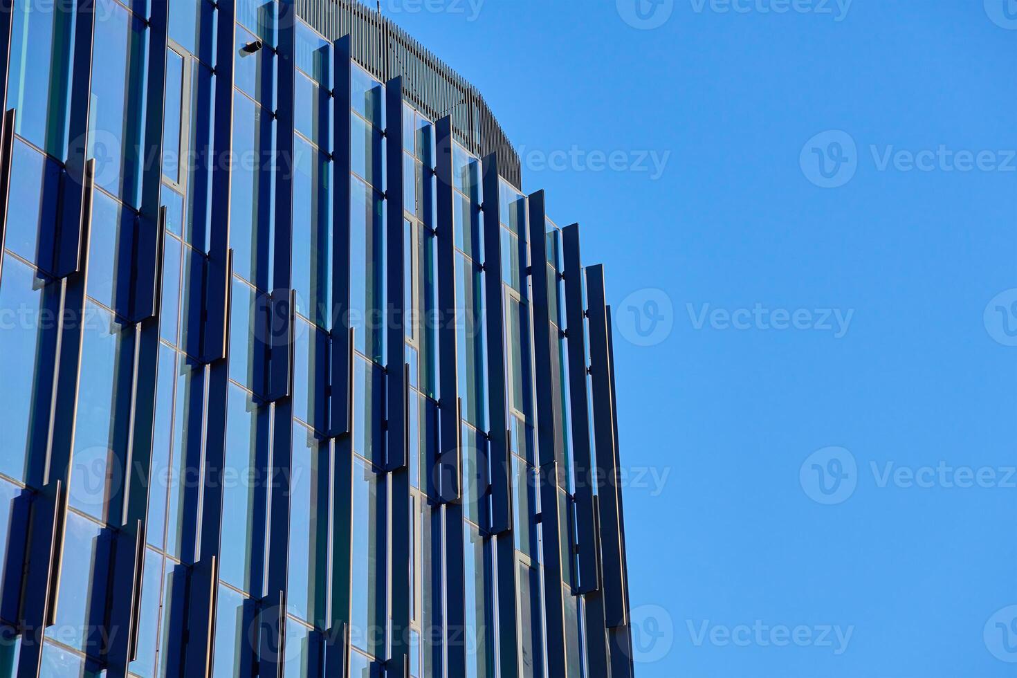 Close-up of modern glass building facade with geometric patterns reflecting sky. Contemporary architectural design. photo