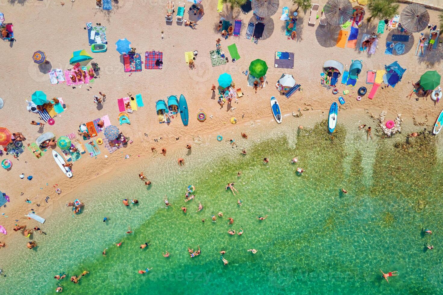 Sea beach with colorful umbrellas and relaxing people, aerial top view. Crowded sandy beach at high season. Tourists at summer holidays in Croatia photo