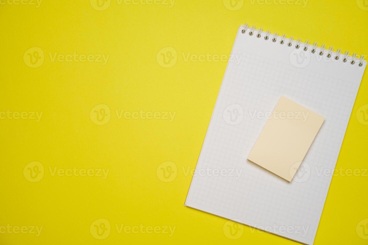 Open blank white notepad on a spiral and stickers on a yellow background. photo