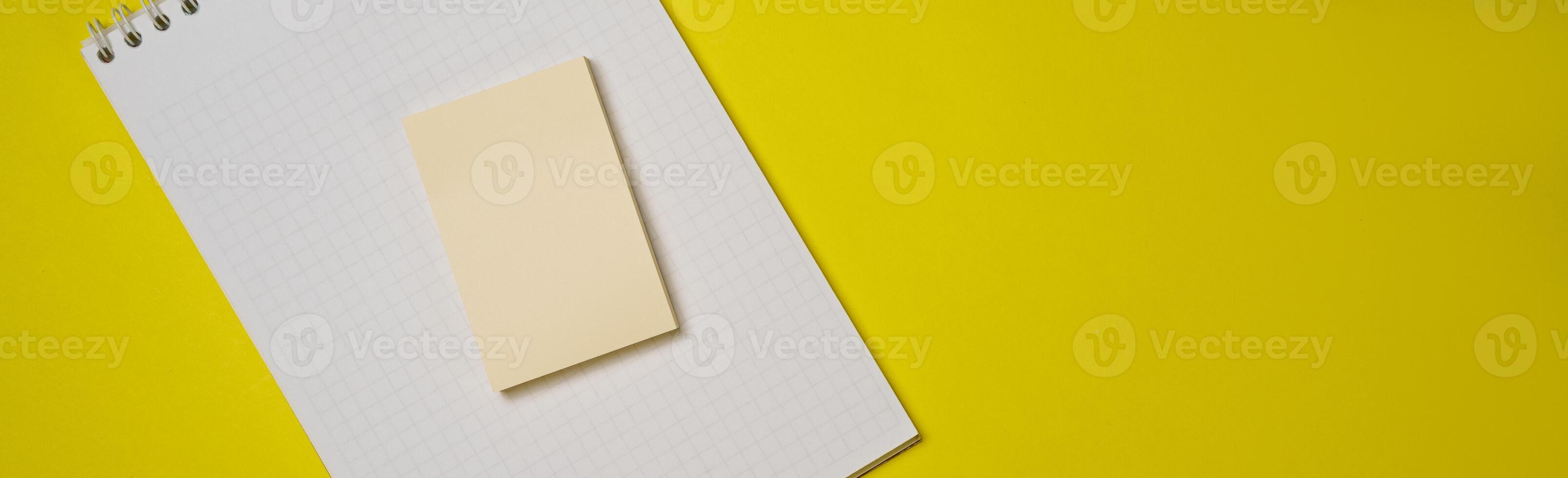 Open blank white notepad on a spiral and stickers on a yellow background. photo