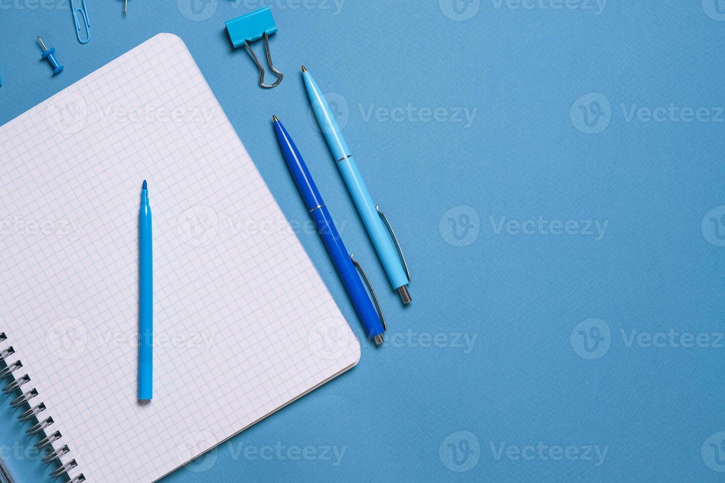 Notebook and pen on a blue background. Top view with copy space. Stationery photo