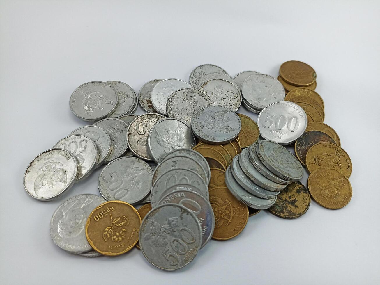 wonosobo, central java indonesia - august 9 2024 a stack of silver and gold coins on a white background. Indonesian Rupiah currency photo