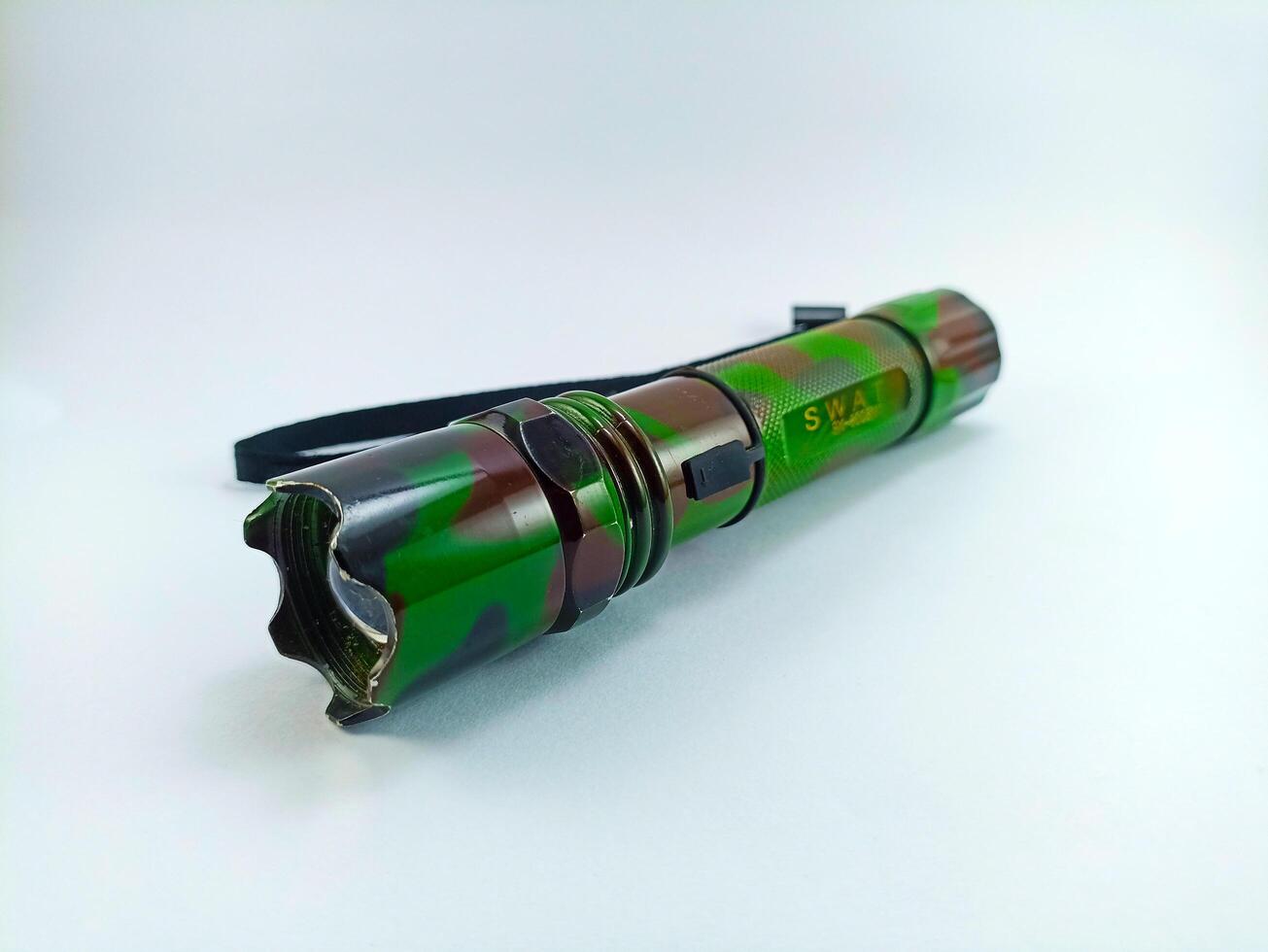 Wonosobo, Central Java, Indonesia - September 7, 2024 Detail of a sturdy green Swat flashlight on a white background. This is a flashlight with a magnifier, waterproof and ready for the toughest jobs photo