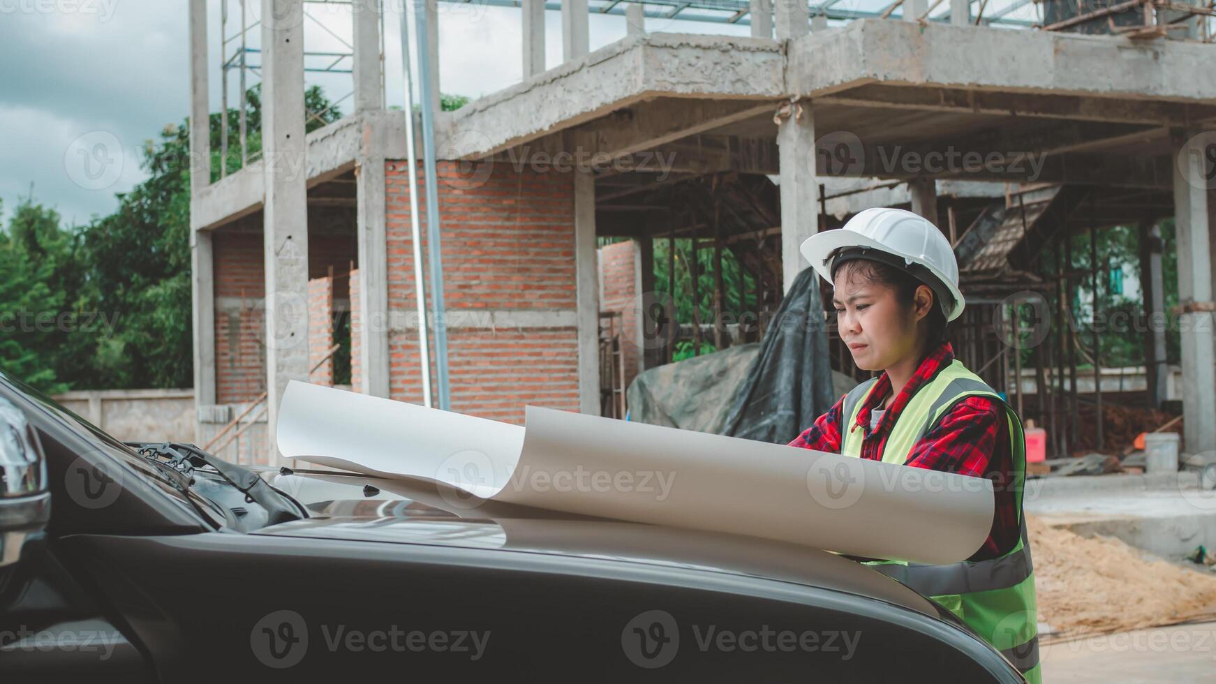 Engineers checking blueprint and planning project working outdoors building side on a worksite, Engineering and architecture concept, Engineer working at site of a large building project. photo