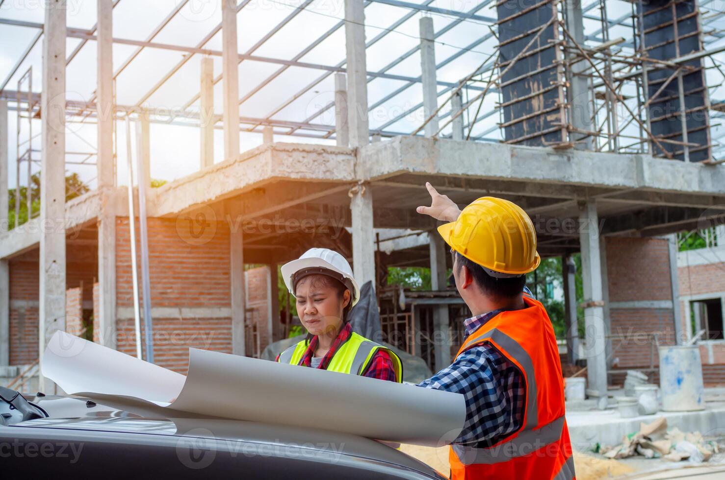 Team engineers holding blueprint project working outdoors building side with blueprints on a worksite, engineering and architecture concept, Engineers having meeting regarding new construction phase photo
