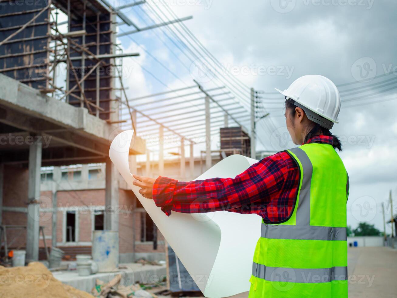 Engineers holding blueprint project working outdoors building side with blueprints on a worksite, Engineering and architecture concept, Engineer working at site of a large building project. photo