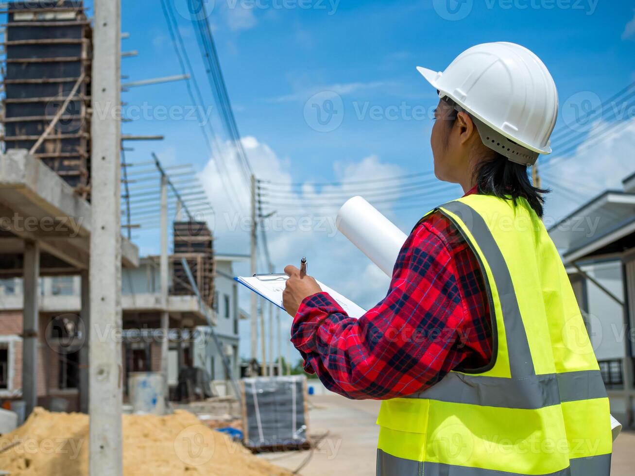 Engineers holding blueprint project working outdoors building side with blueprints on a worksite, Engineering and architecture concept, Engineer working at site of a large building project. photo
