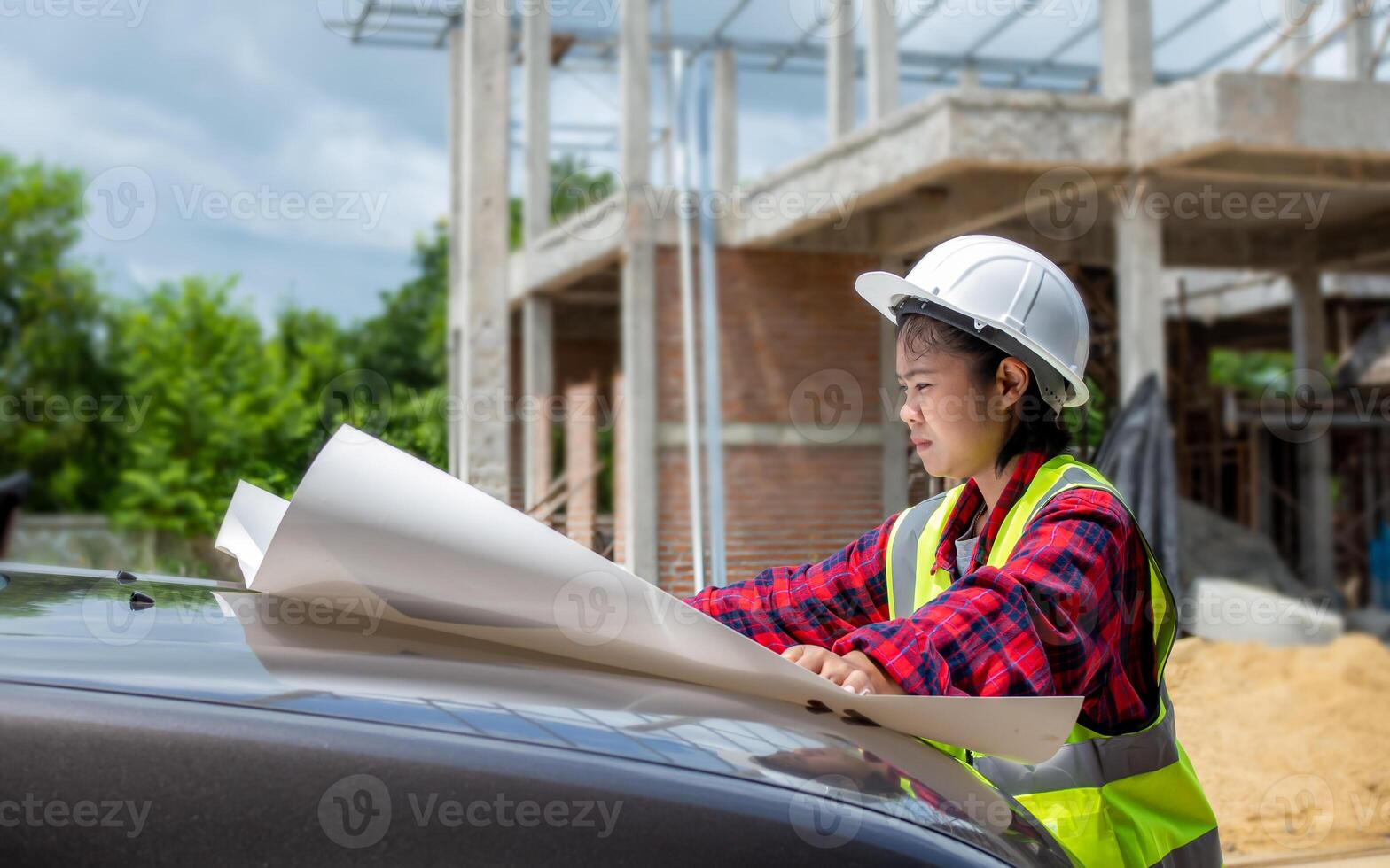 Engineers checking blueprint and planning project working outdoors building side on a worksite, Engineering and architecture concept, Engineer working at site of a large building project. photo