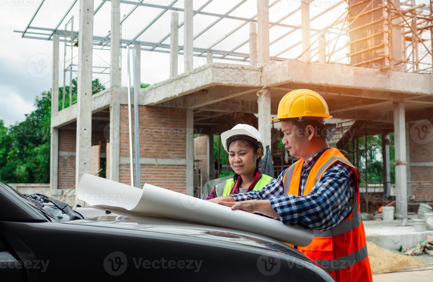 Team engineers checking blueprint and planning project working outdoors building side on a worksite, Engineering and architecture concept, Engineers having meeting regarding new construction phase. photo