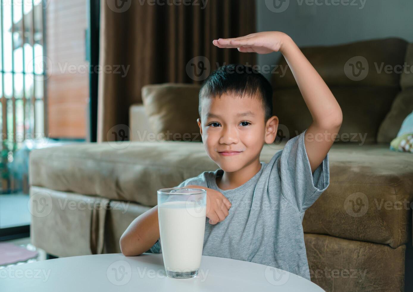 Portrait of a little young handsome kid boy in pink t-shirt, Concept of happy good nutrition, Holding a glass of milk on grey background, Smiling of Asian boy with a glass of milk. photo