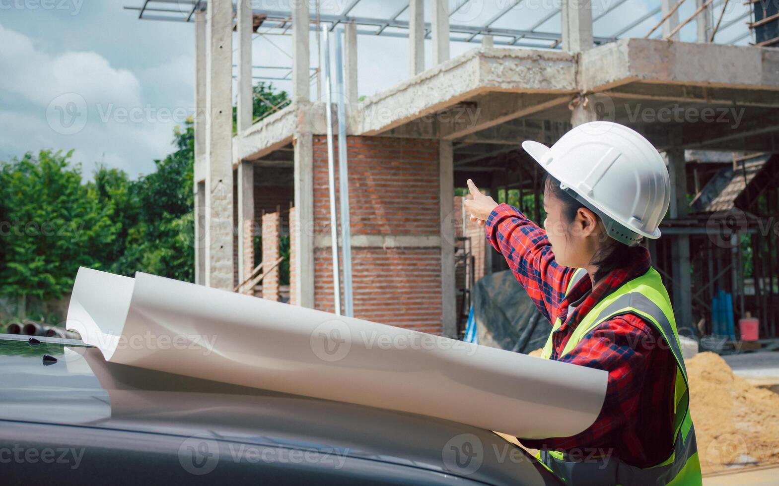 Engineers checking blueprint and planning project working outdoors building side on a worksite, Engineering and architecture concept, Engineer working at site of a large building project. photo