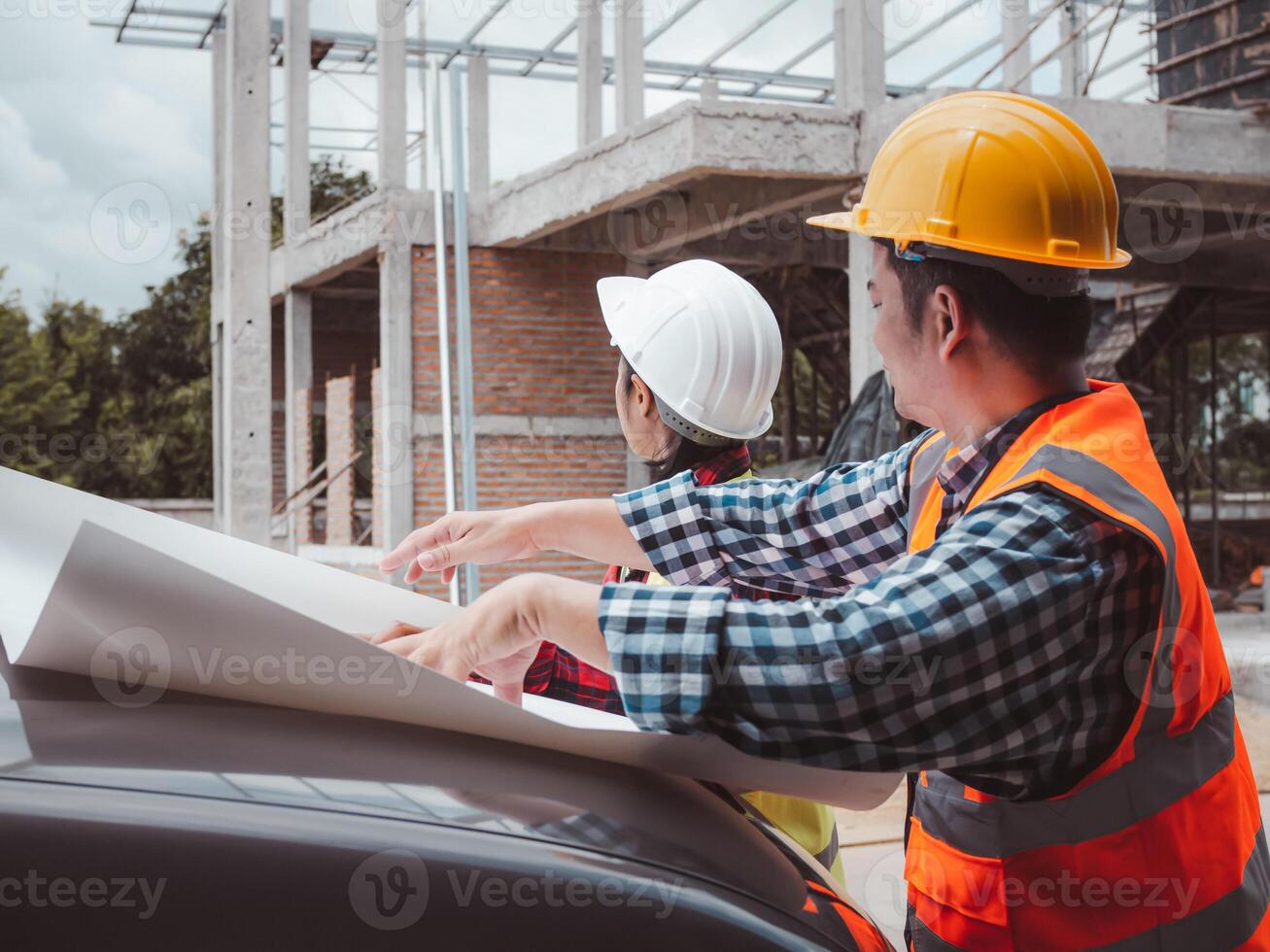 Team engineers checking blueprint and planning project working outdoors building side on a worksite, Engineering and architecture concept, Engineers having meeting regarding new construction phase. photo