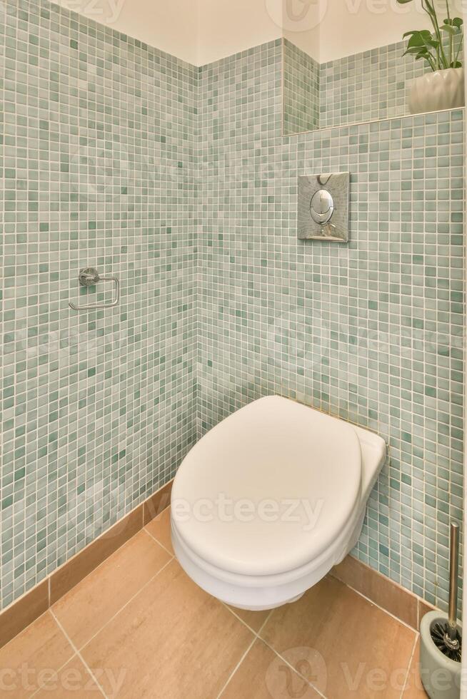 A bathroom with a toilet and a green tile wall photo