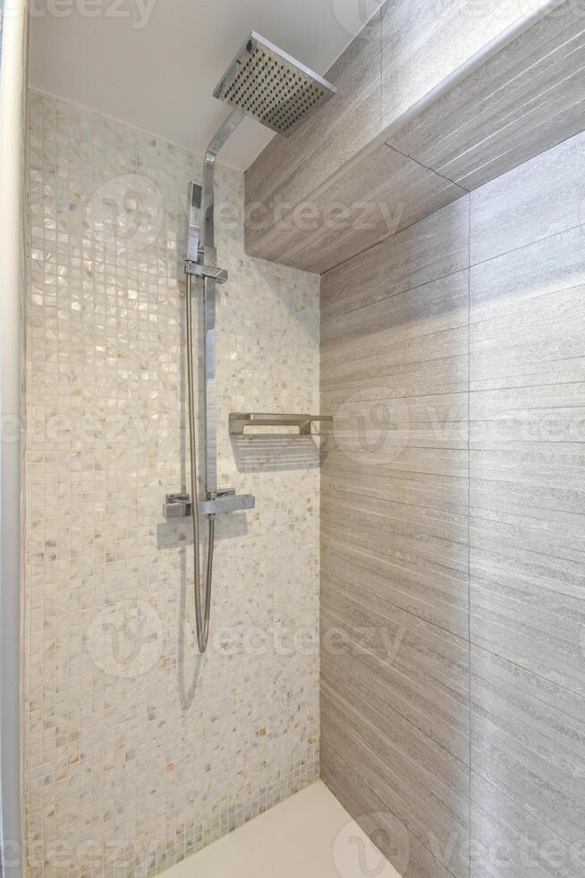 A shower with a glass wall and a shower head photo