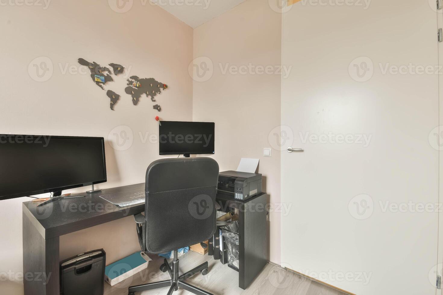A home office with a desk, computer and a world map photo