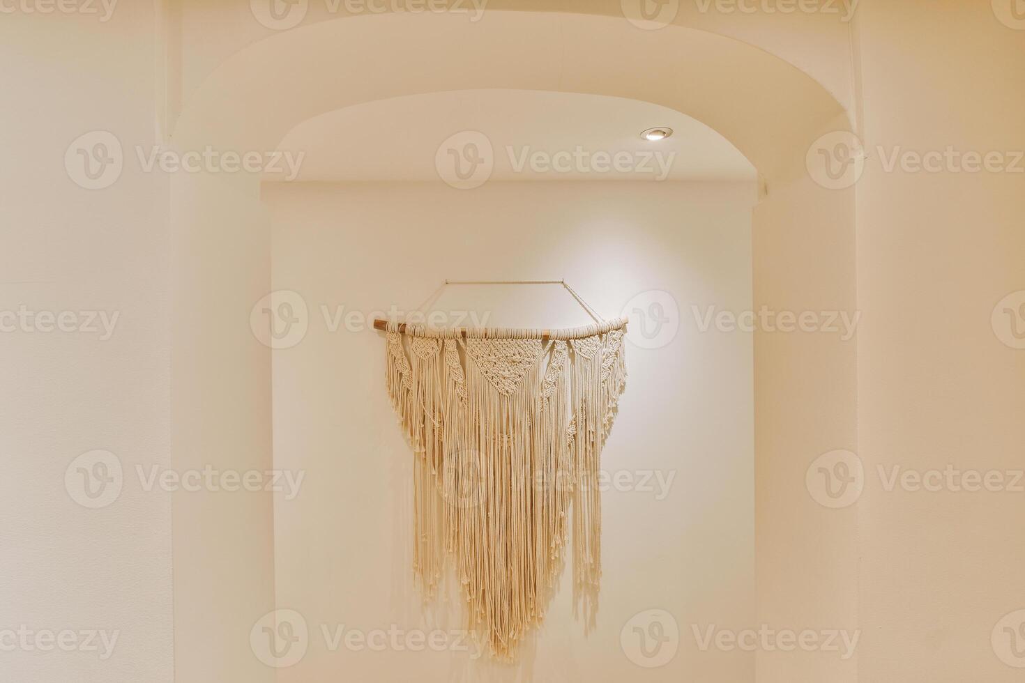 A white wall with a large white macrame hanging on it photo
