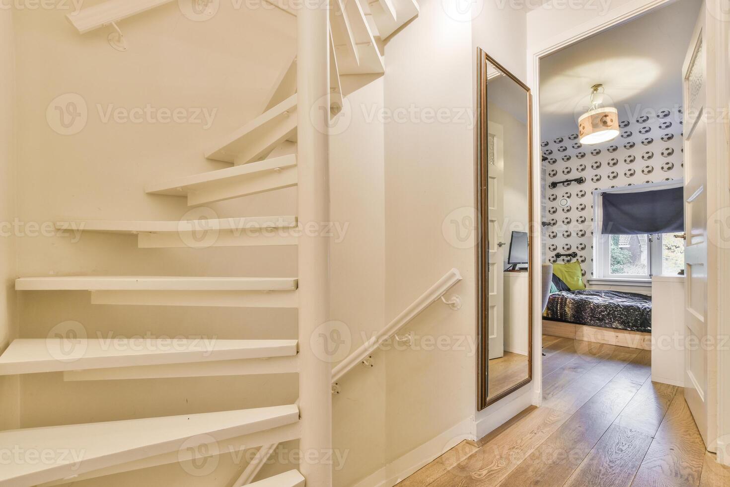 A narrow hallway with a staircase and a bed photo