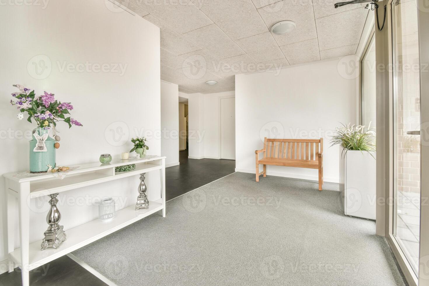 A hallway with a bench and a vase on the floor photo