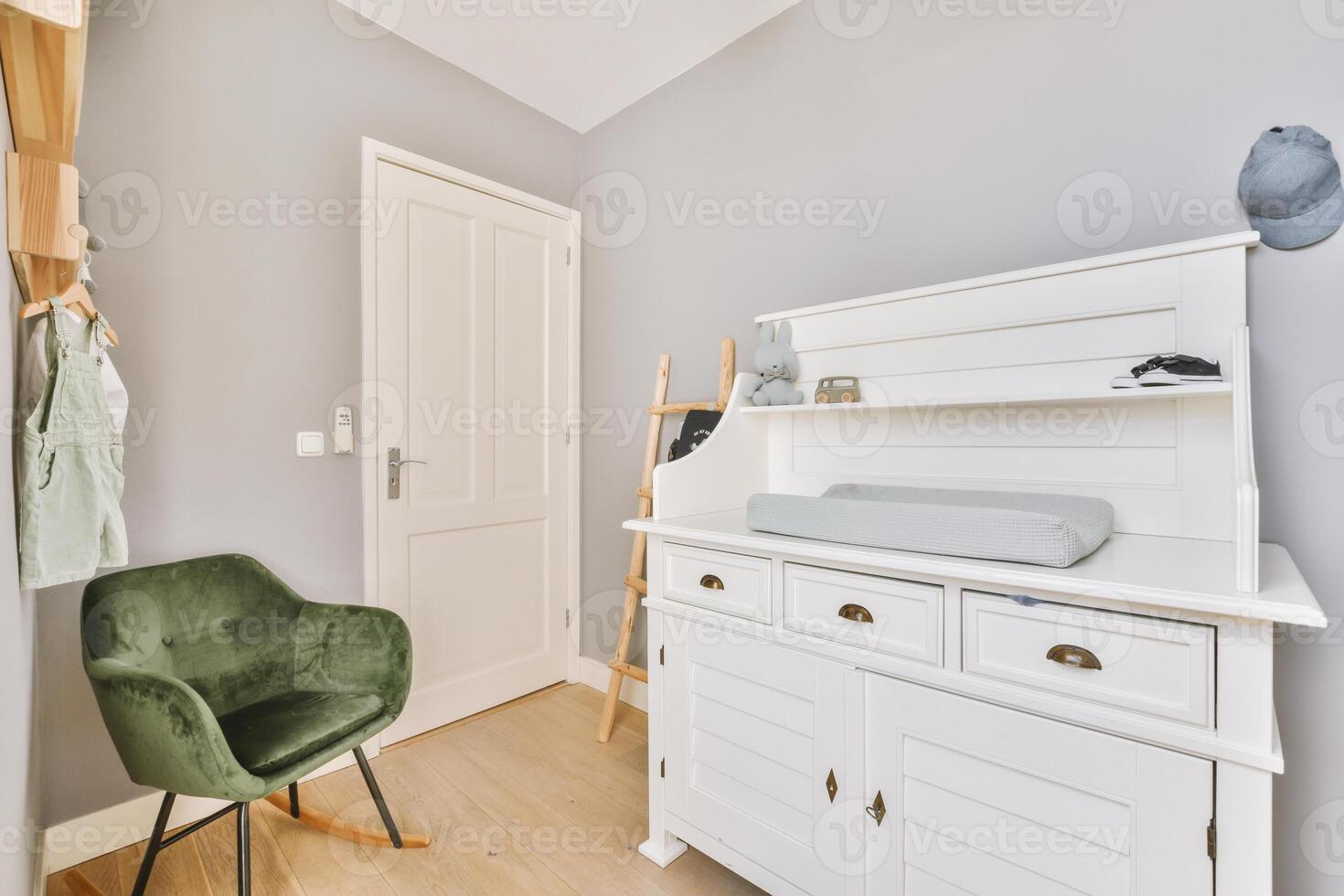 A small white dresser with a green chair in it photo