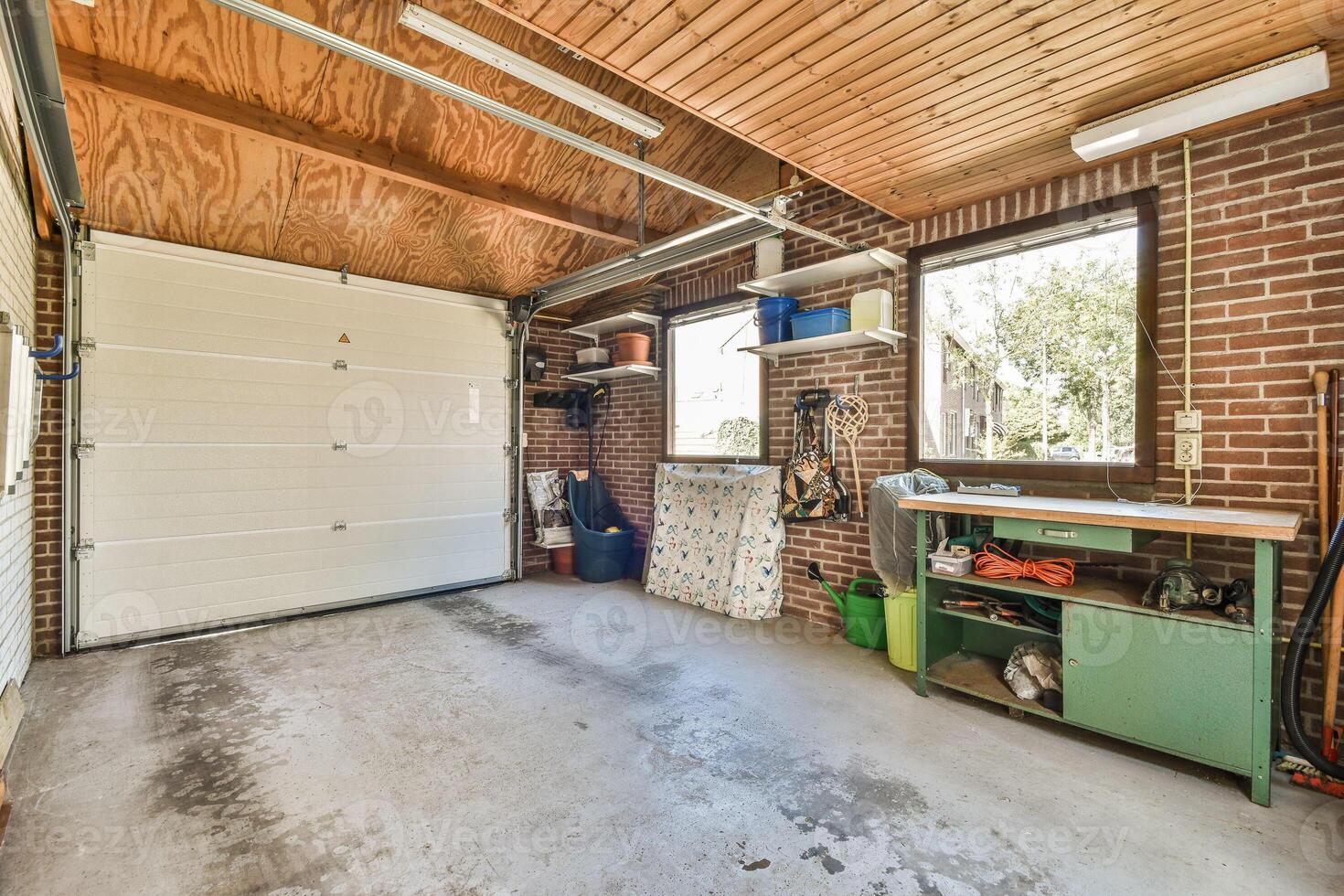 A garage with a large open door and a work bench photo