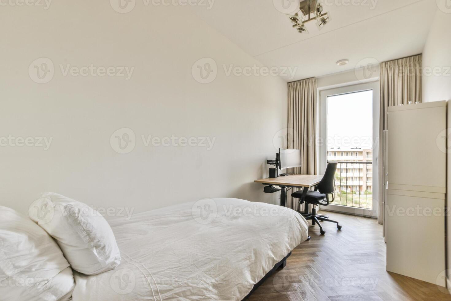 A bedroom with a bed, desk and window photo