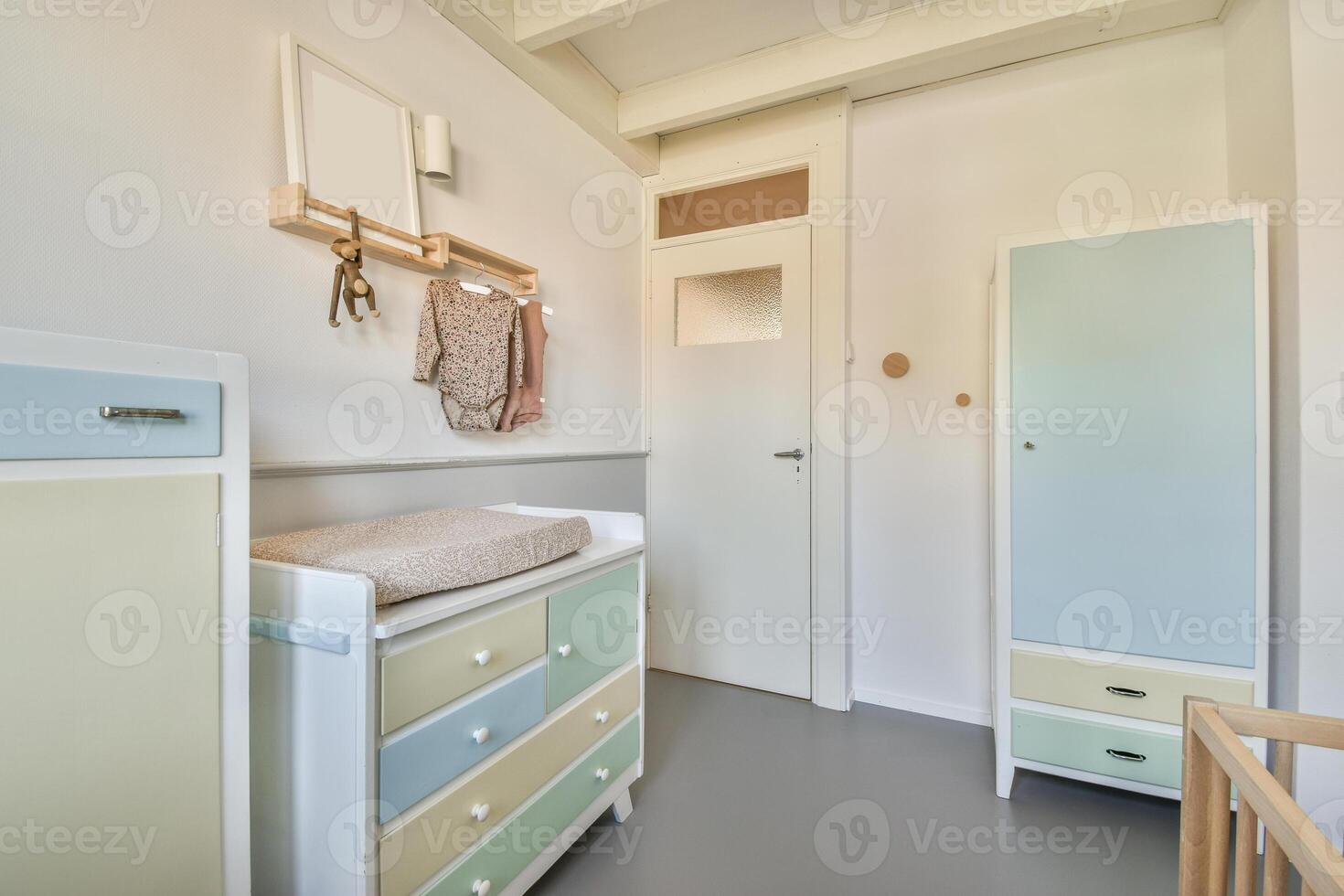 A small room with a dresser, a chest of drawers and a baby's crib photo