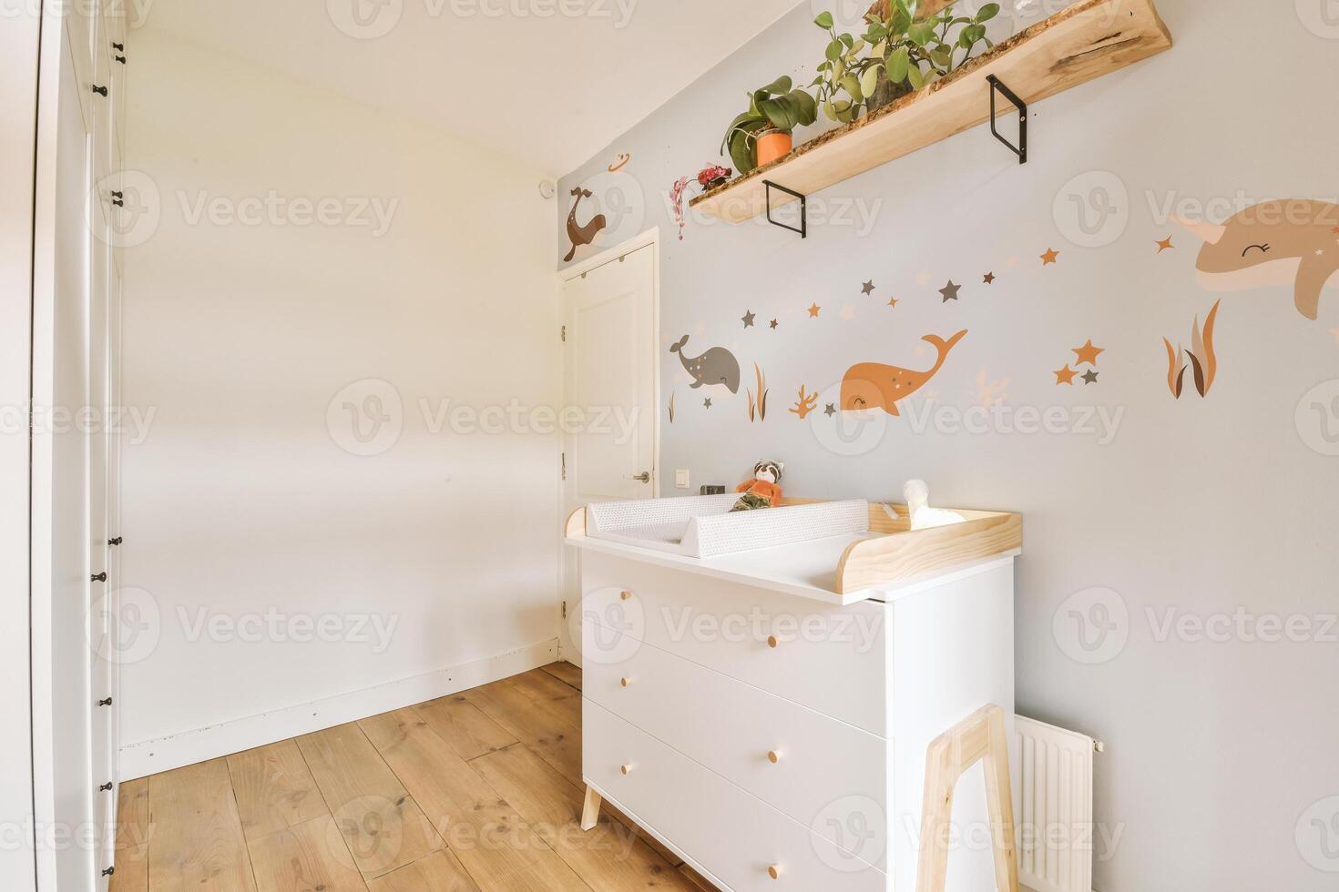 A small nursery with a wooden floor and white dresser photo